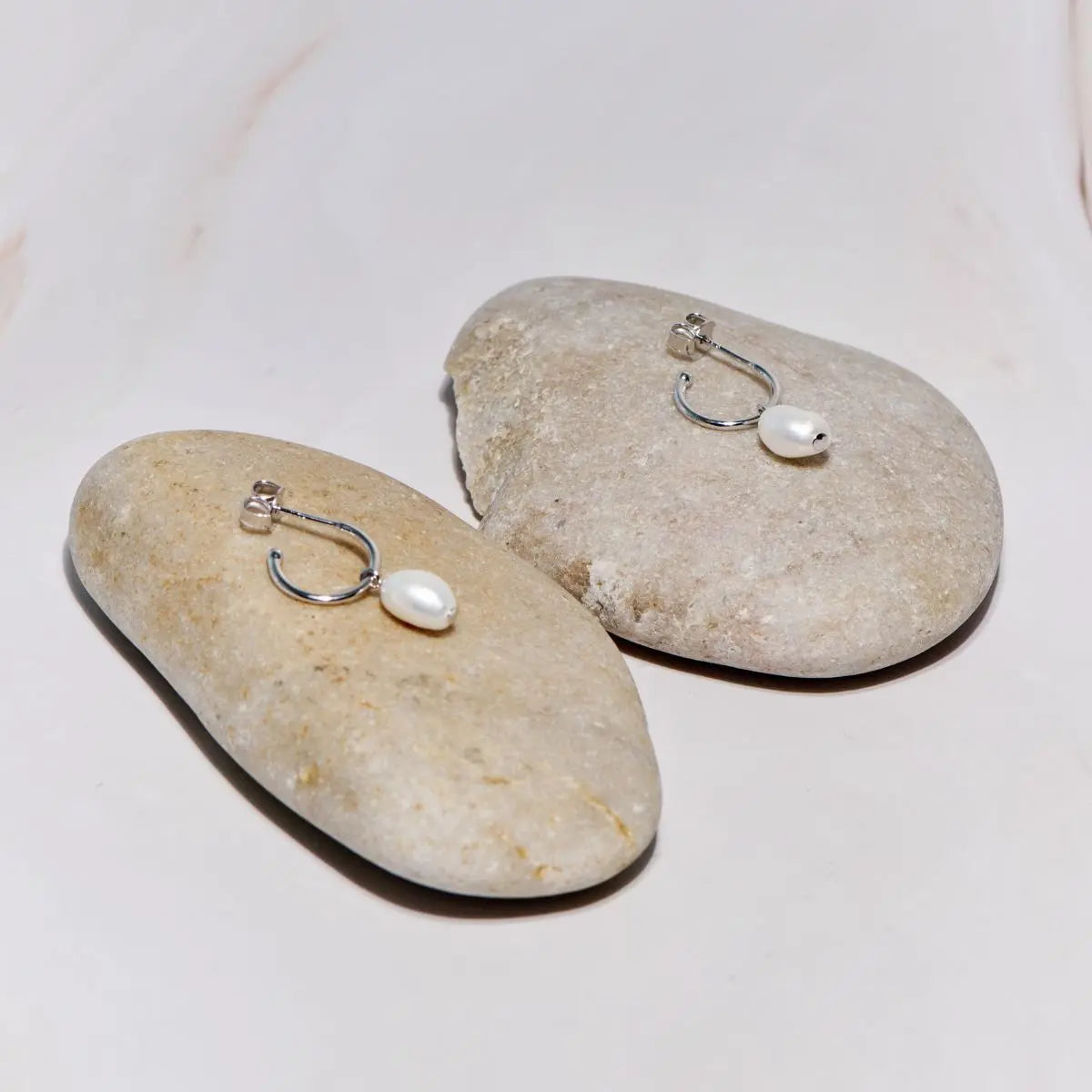 Pearl earrings on stones with a white background