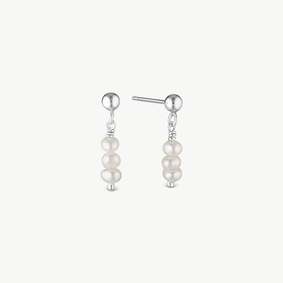 A pair of silver drop earrings featuring three stacked white pearl beads on each earring, shown against a plain off-white background.