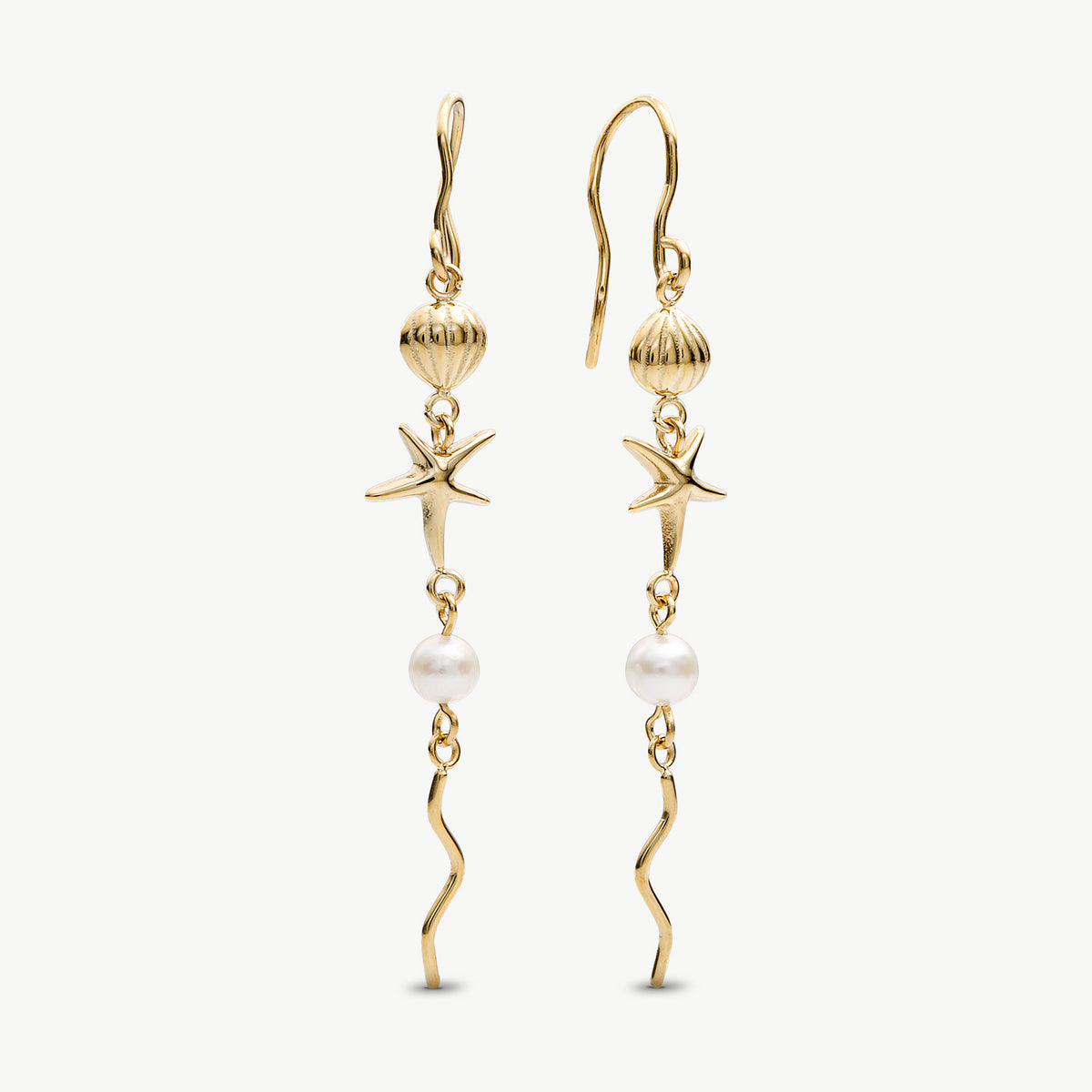 A pair of gold dangle earrings featuring starfish, seashell, pearl, and wavy chain details, shown against a plain off-white background.
