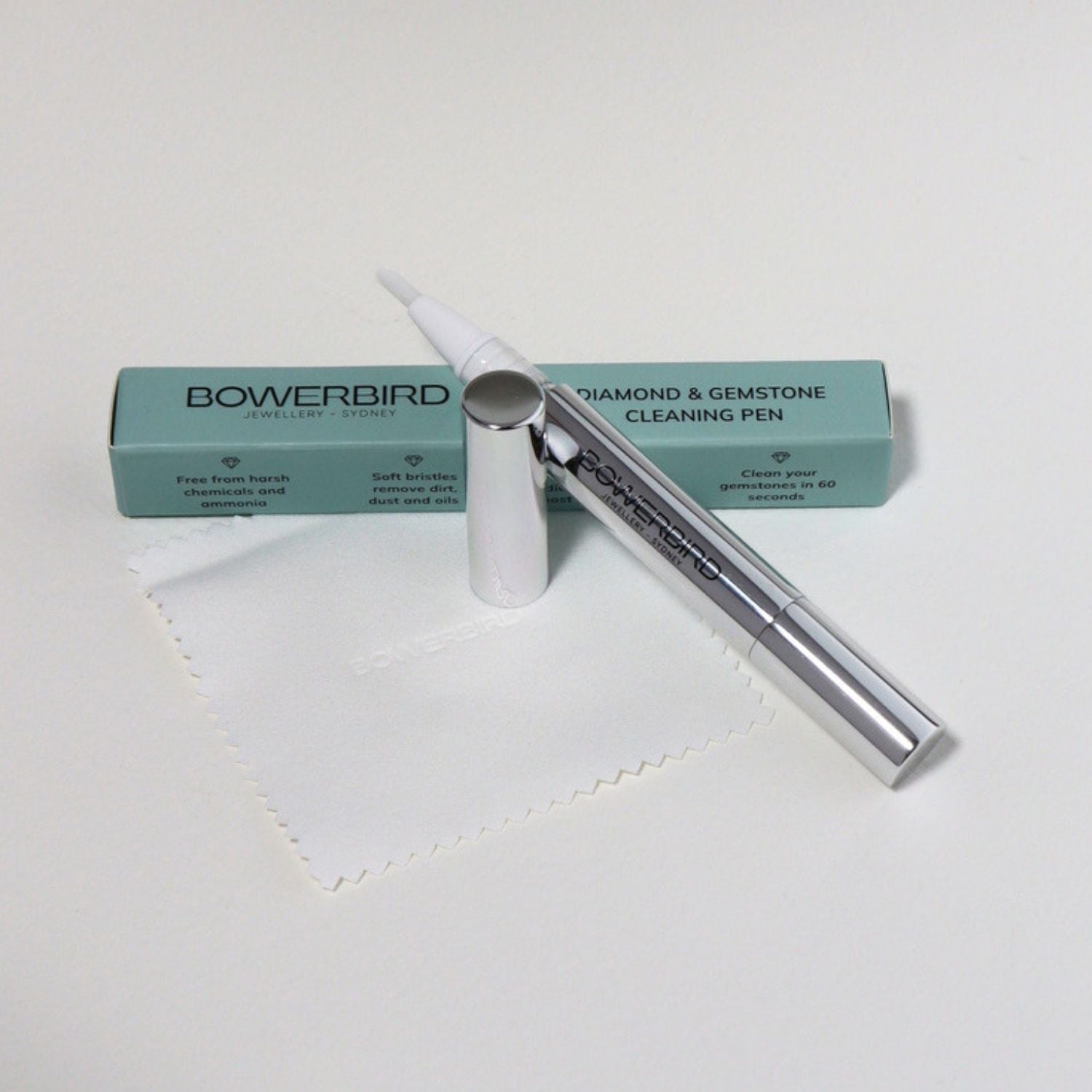 Bowerbird Diamond & Gemstone Cleaning Pen with its mint green packaging box and a white microfiber cloth on a clean white background.