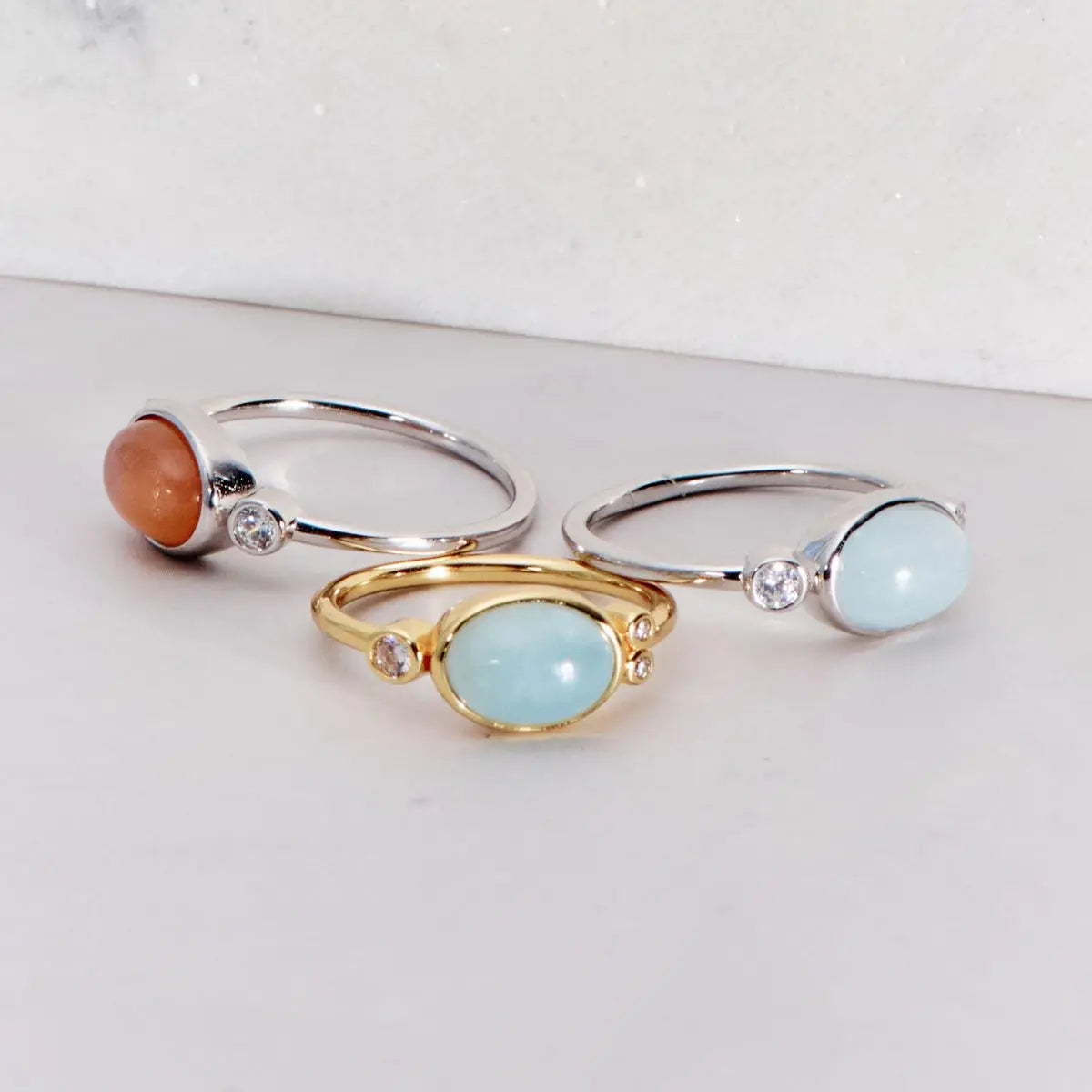 Three rings with gemstones on a light gray background