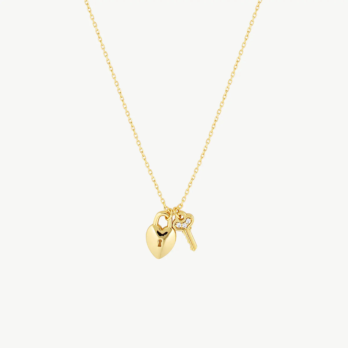 Hanging gold lock with key necklace suspended from chain against a cream background