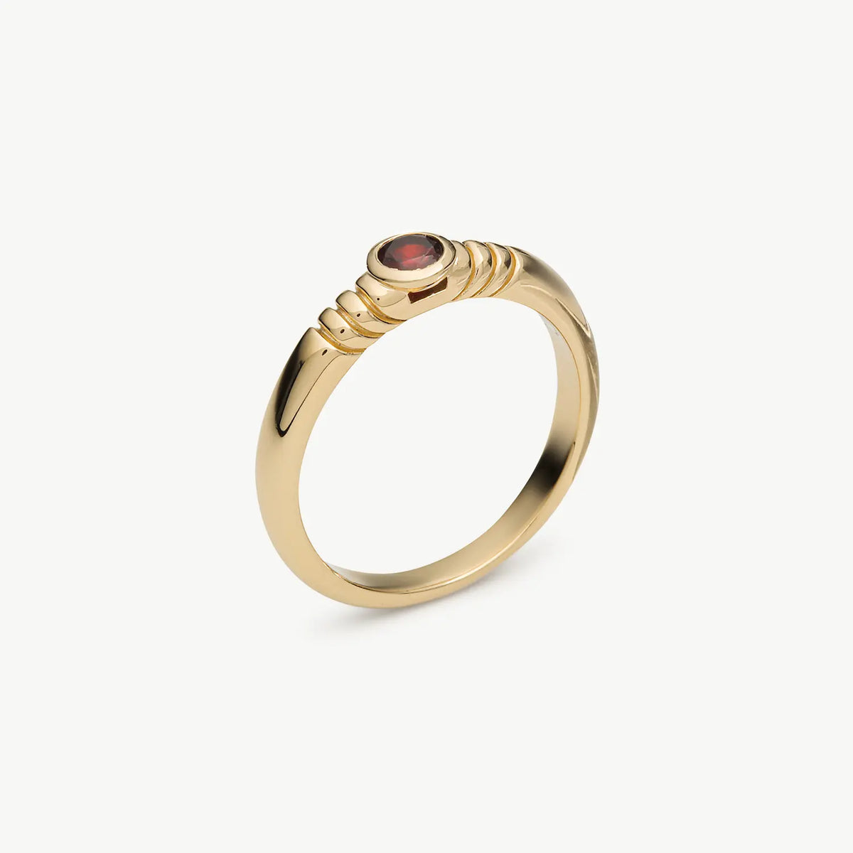 A gold ring with a textured, rope-like band and a small round red gemstone in the center, shown on a clean off-white background.