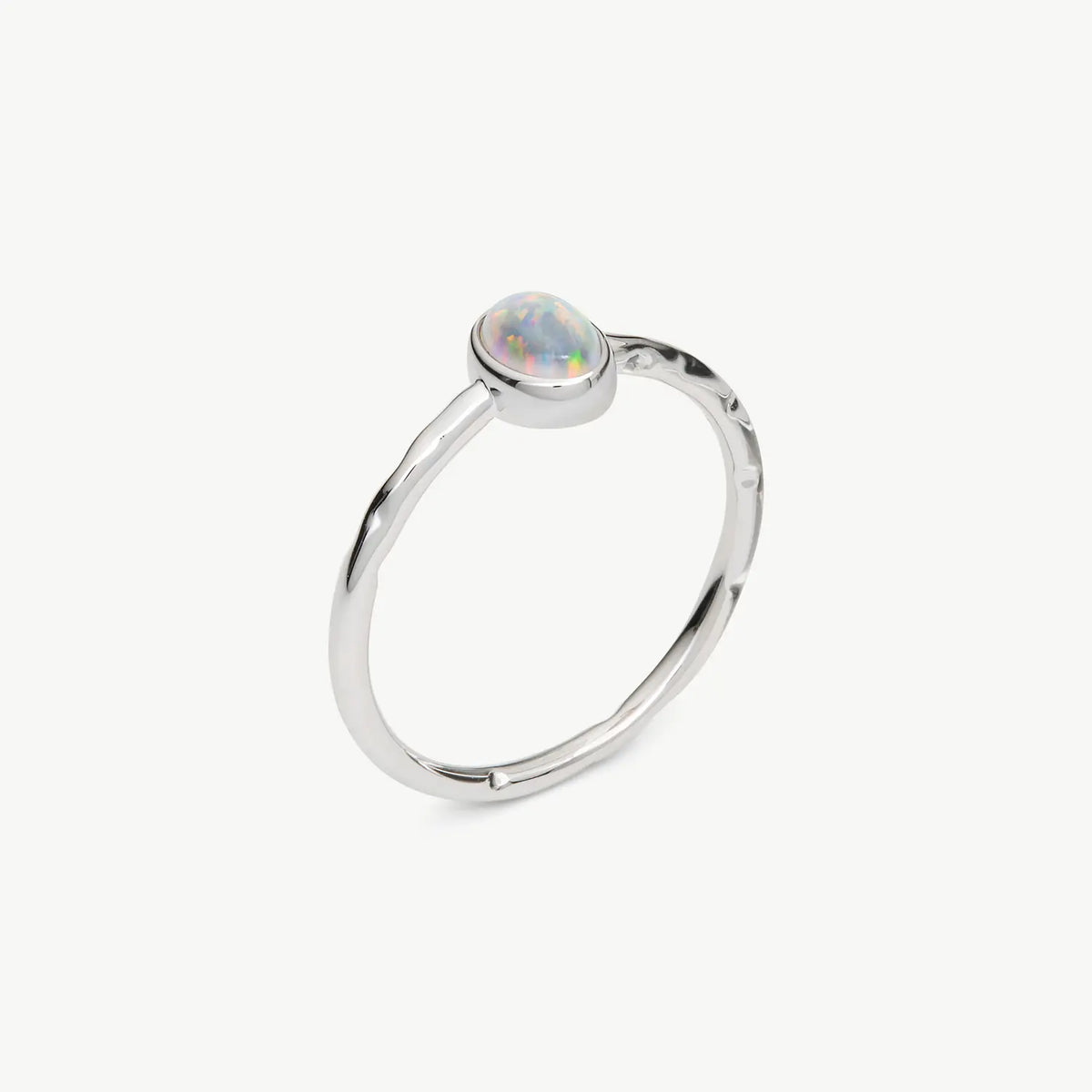 A silver ring featuring a small, oval-shaped iridescent opal gemstone in a bezel setting, shown on a clean off-white background.