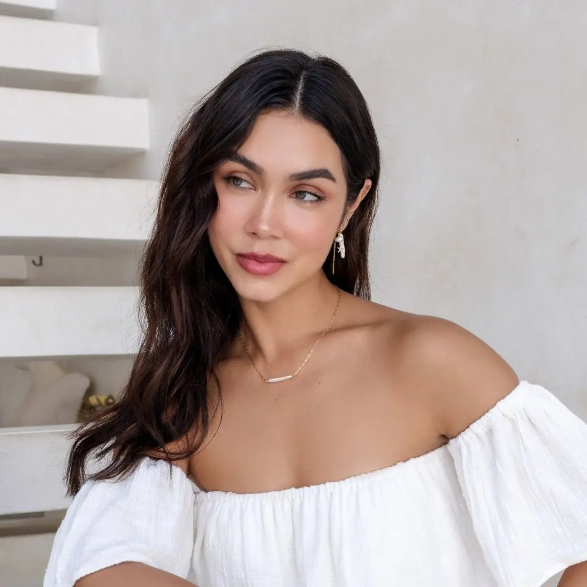 Woman wearing a white off-shoulder top with a neutral background