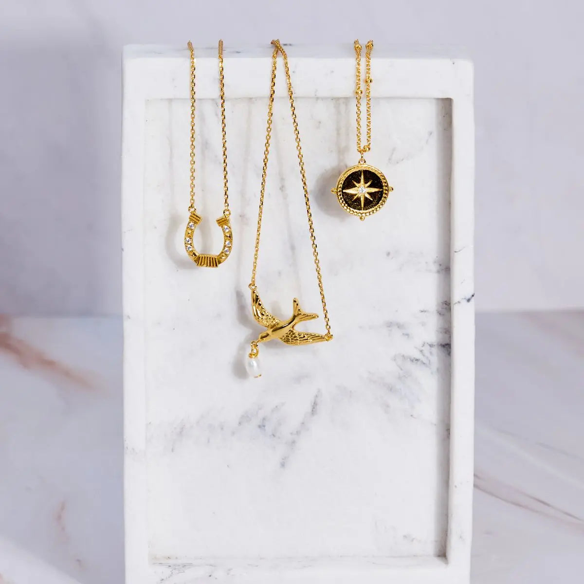 Three gold necklaces on a marble surface