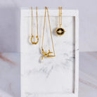 Three gold necklaces on a marble surface