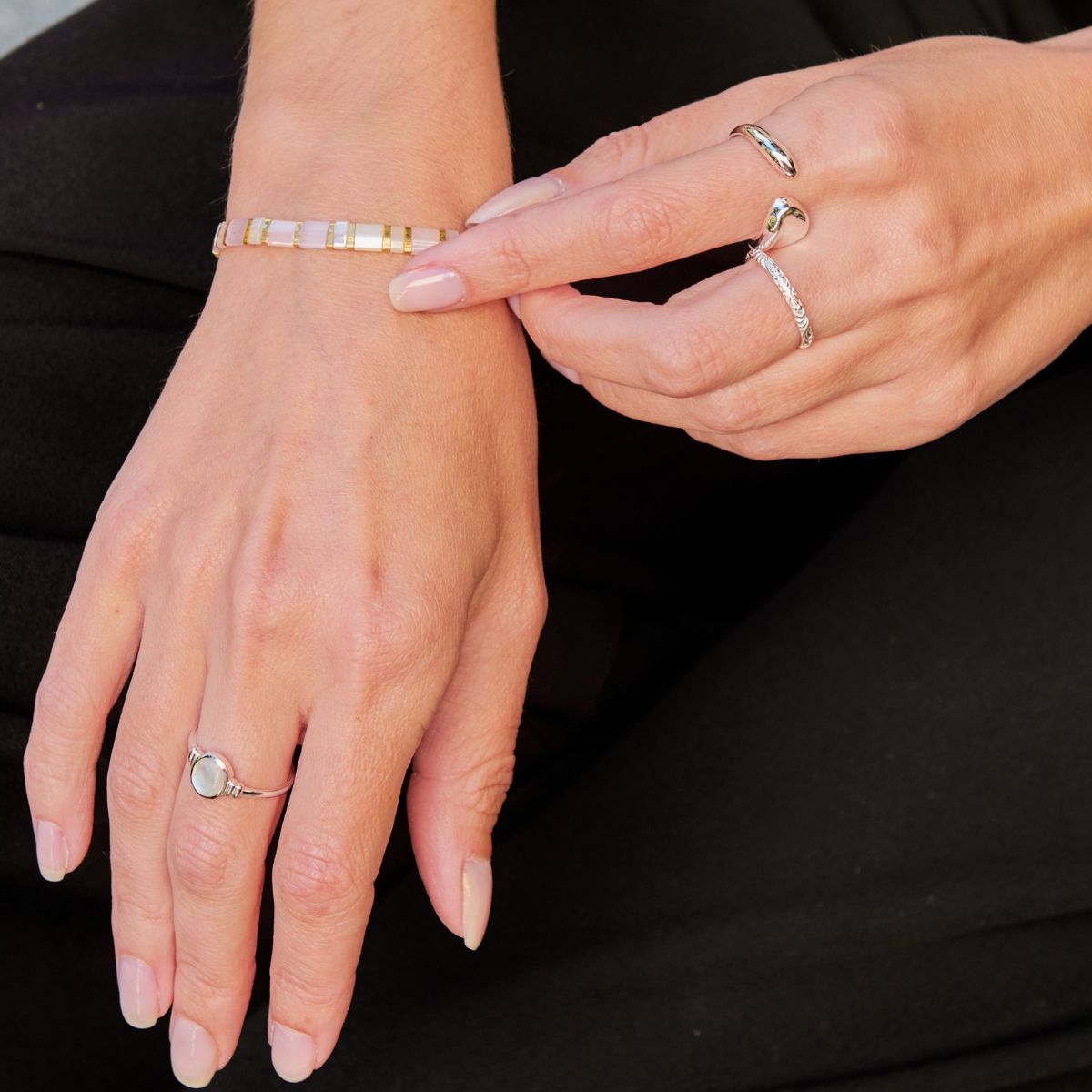 Close-up of hands wearing multiple rings on a black background