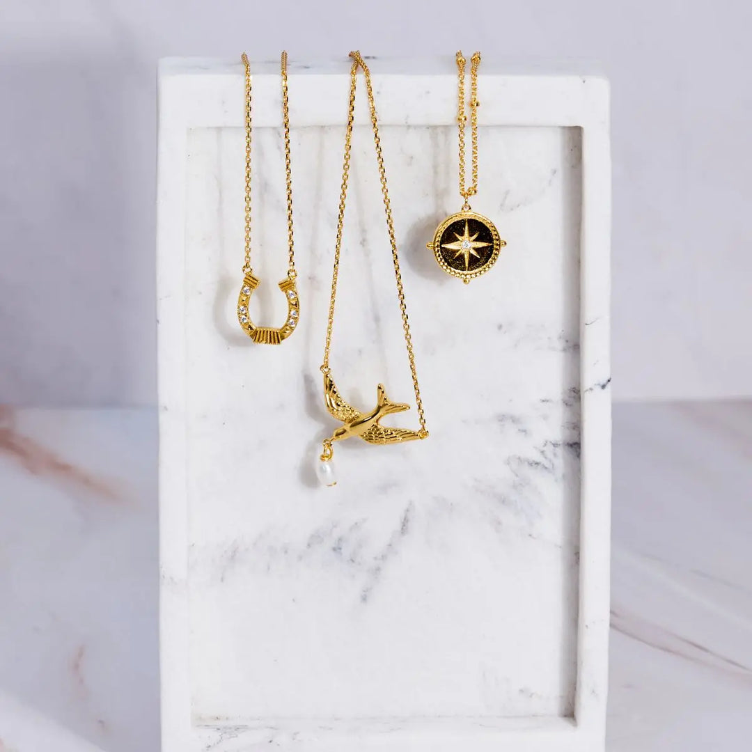 Three gold necklaces on a marble surface