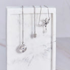 Three silver necklaces on a marble surface