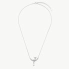 A delicate silver chain necklace featuring a small bird pendant with a teardrop-shaped clear stone hanging from its beak, displayed against a solid off-white background.