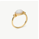 A gold ring featuring an oval cabochon opal with iridescent white, blue, and pink flashes, accented by two small round clear stones on the band, set against a light gray background.