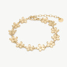 A gold-tone flower-link bracelet with five-petal flower charms and an adjustable lobster clasp, shown on a clean off-white background.