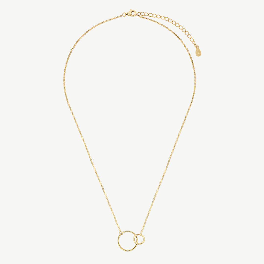 A delicate gold chain necklace featuring two interlocking open circular pendants, displayed on a clean, light off-white background.