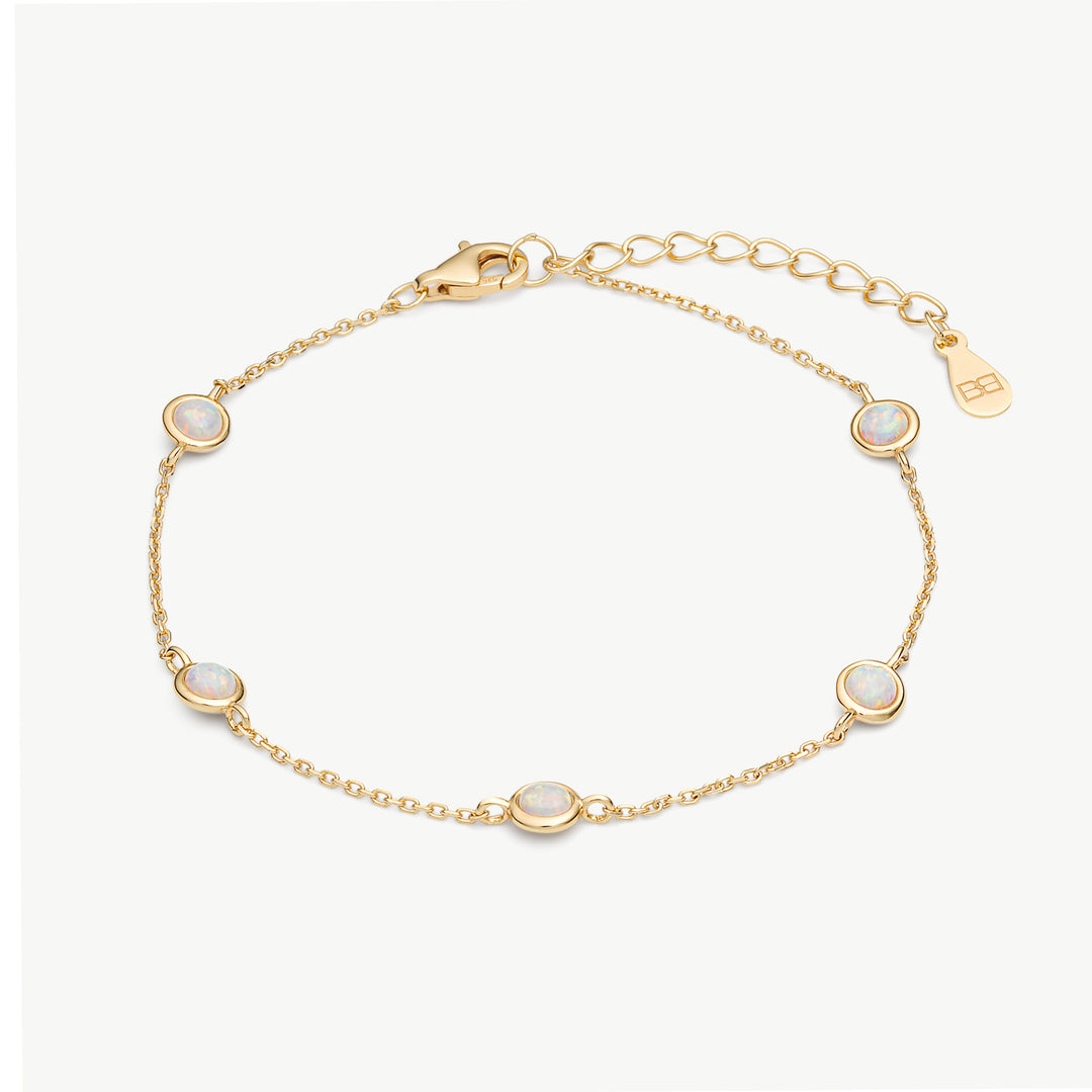A delicate gold chain bracelet with five oval white opal-like stones, displayed on a clean off-white background. The bracelet features a lobster clasp, an adjustable link chain extender, and a small gold brand tag engraved with 'BH'.
