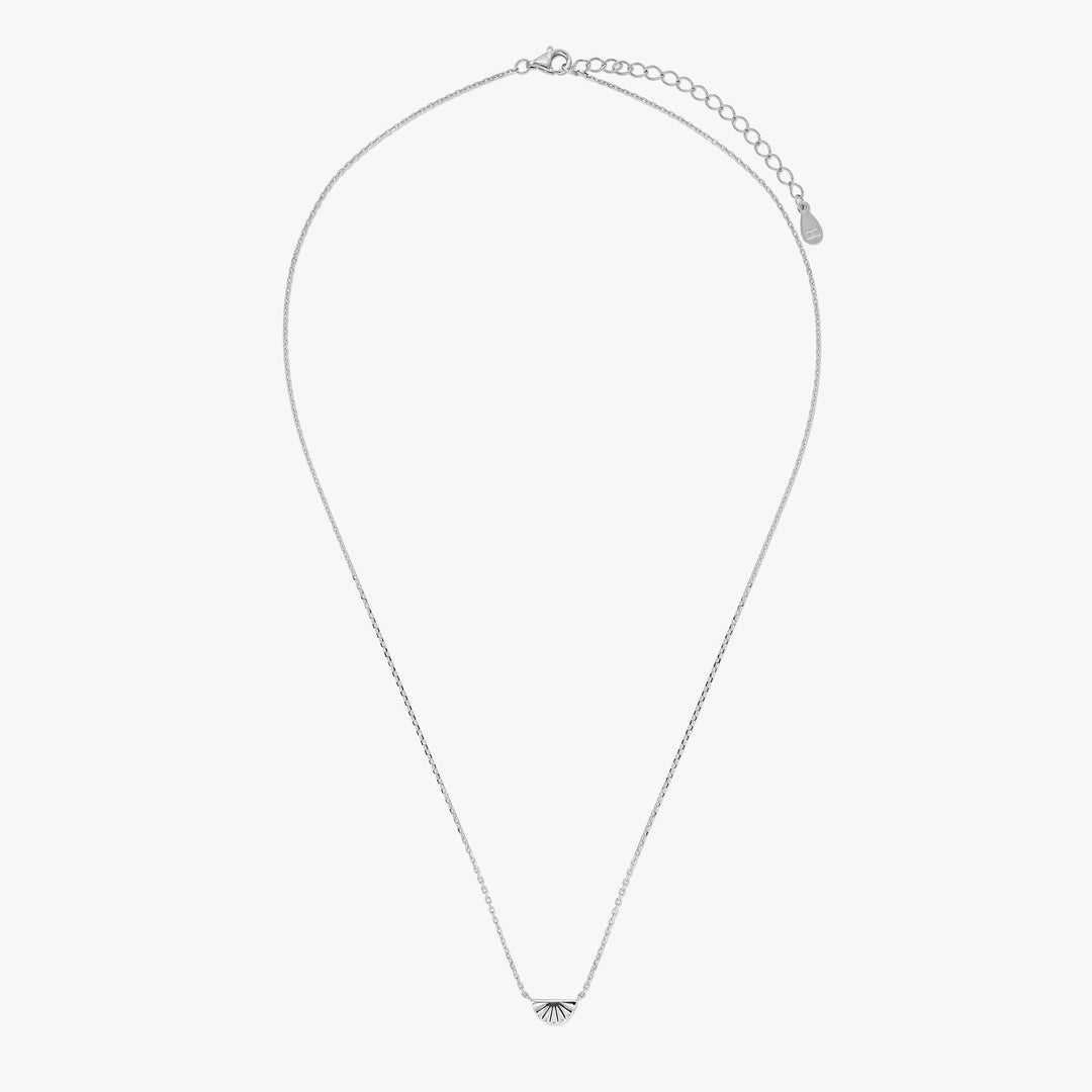 A delicate silver chain necklace with a small, minimalist fan-shaped pendant at the center, displayed on a clean, light off-white background.