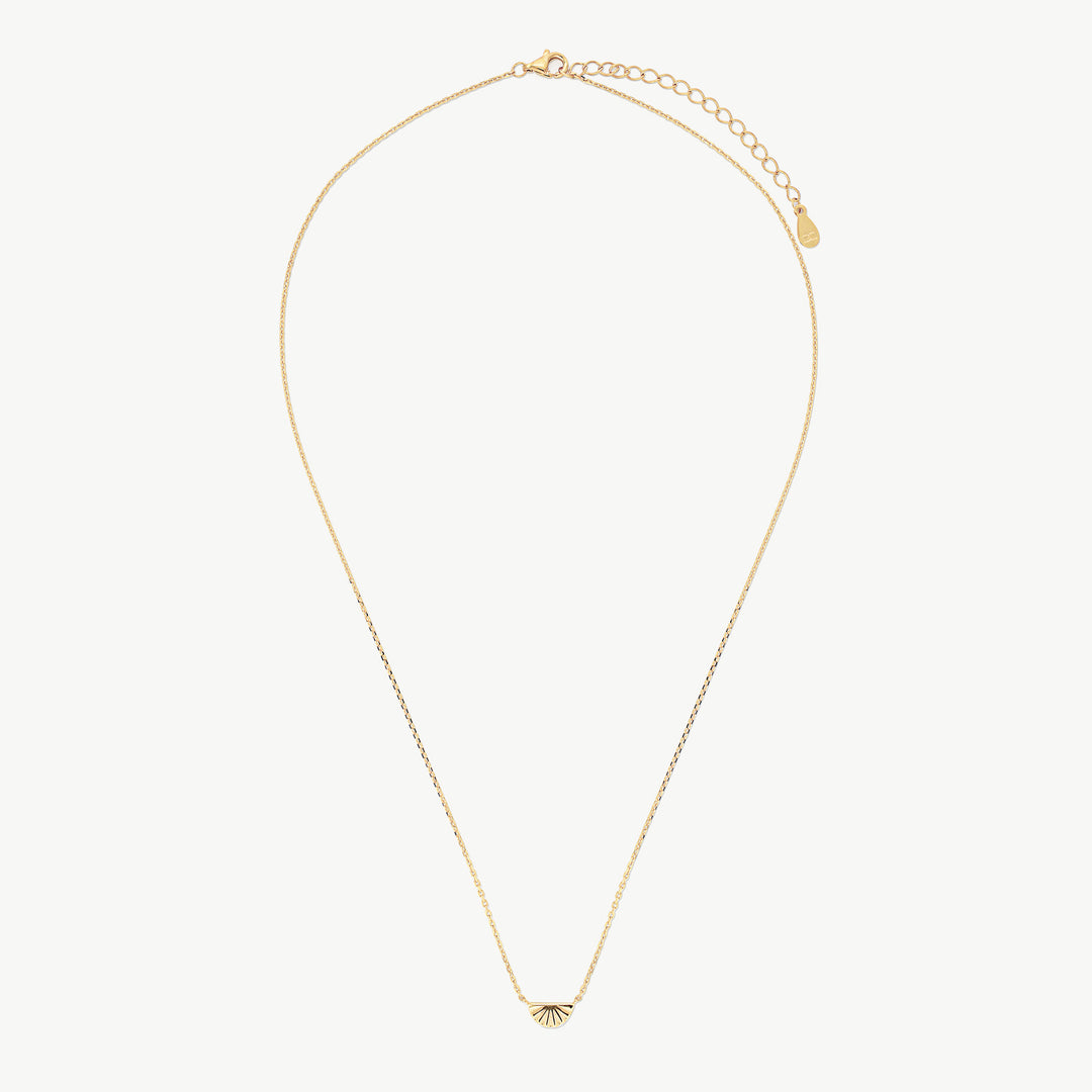 A delicate gold chain necklace with a small fan-shaped pendant, displayed on a clean off-white background.
