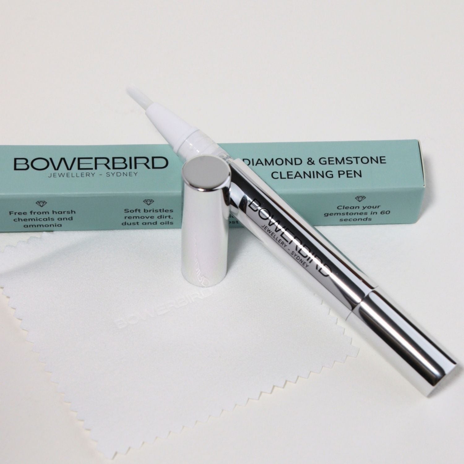 Bowerbird Jewellery Store Diamond & Gemstone Cleaning Pen shown with its mint green box and a white microfiber cloth on a white background.