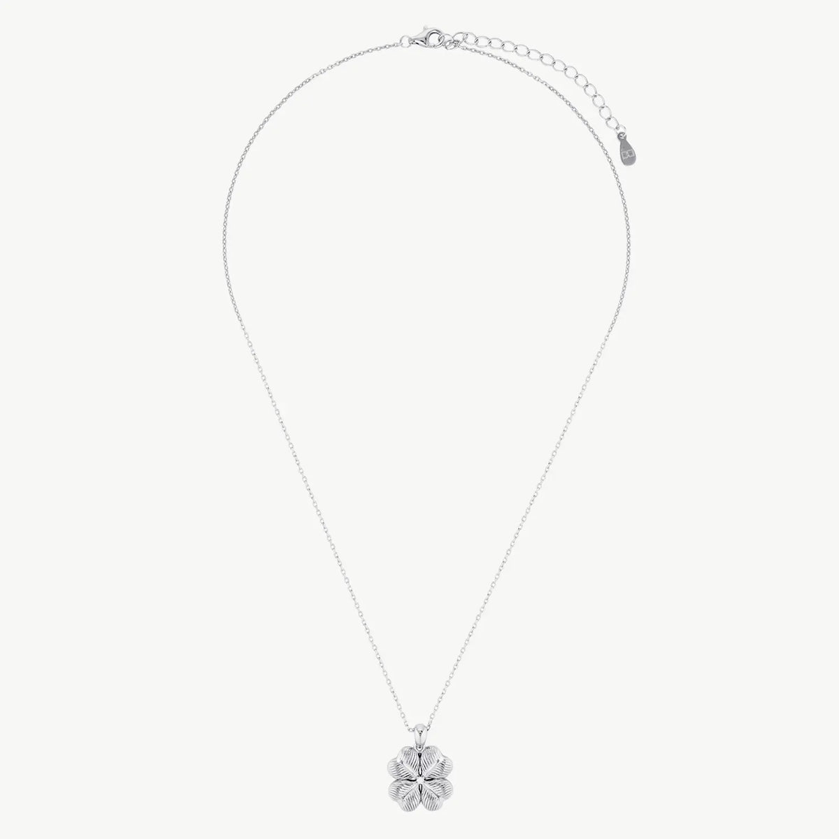 A ridged four-leaf clover with a white stone centre hanging from a silver-coloured chain on a cream background 