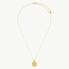 A ridged four-leaf clover charm with a cubic zirconia centred gemstone hanging from a fine yellow gold cable chain on a cream background 