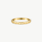 A delicate yellow gold band ring with a geometric openwork pattern, photographed on a clean, light off-white background.