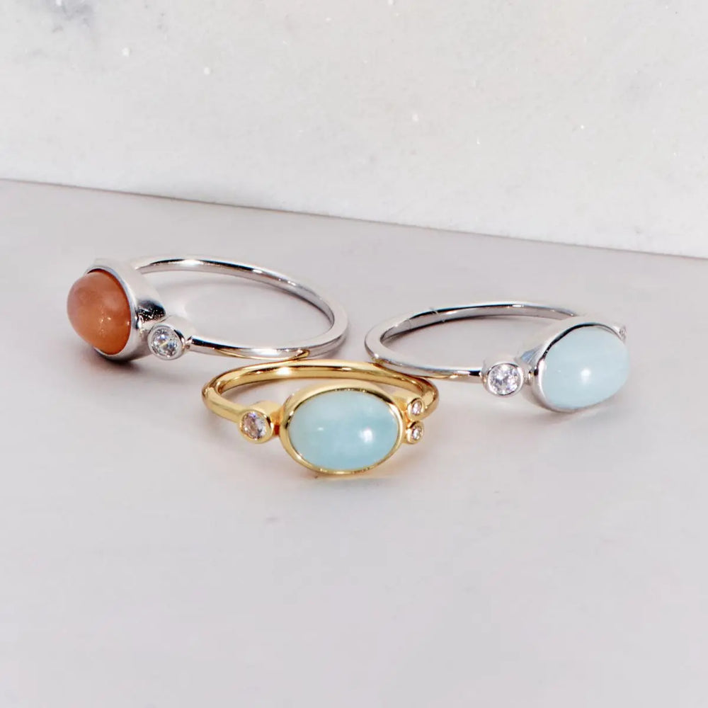 Three rings with gemstones on a light gray background