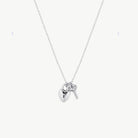 Hanging silver lock necklace with key charm suspended from silver chain against a cream background 