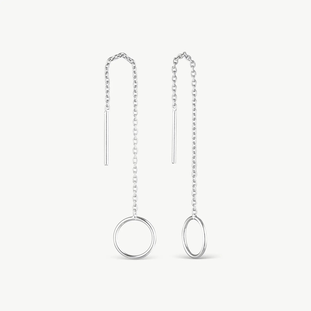 A pair of silver dangle earrings with a minimalist design, featuring a short vertical bar, a beaded chain, and a larger round ring at the bottom, displayed on a clean off-white background.