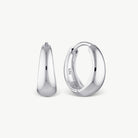 A pair of polished silver huggie hoop earrings shown from front and side views on a clean, light off-white background.