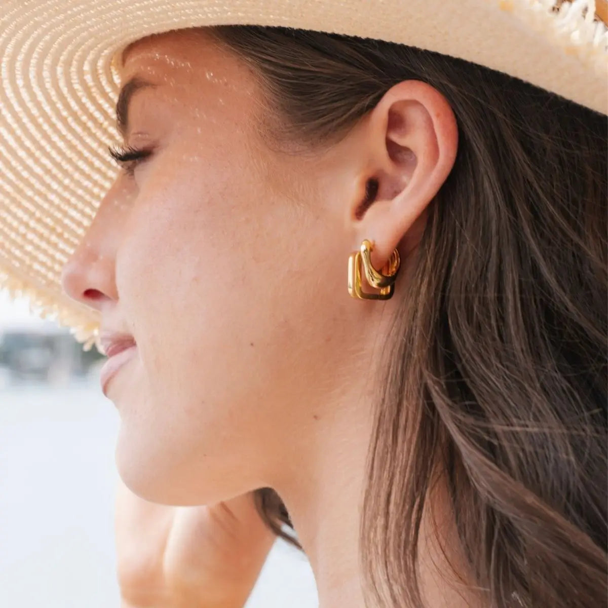 Close-up of a woman wearing gold hoop earrings with a blurred background