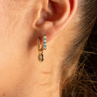 A close-up lifestyle shot of a woman wearing a delicate gold ring with a small oval light blue stone on her finger.