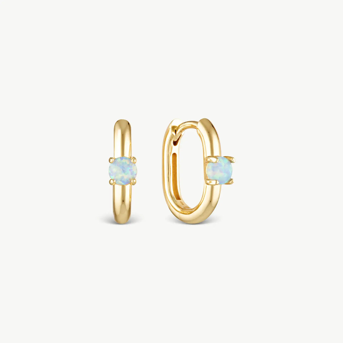 A pair of gold huggie hoop earrings, one shown from the front and the other from the side, each featuring a small oval light blue opal stone in a prong setting, on a clean off-white background.