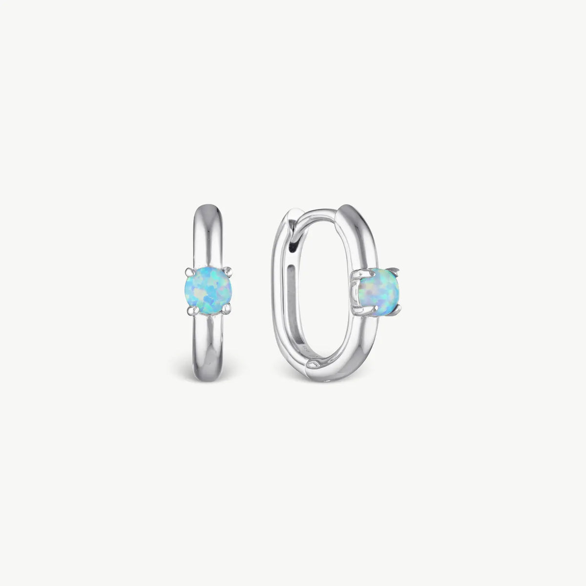 A pair of silver huggie hoop earrings, one shown from the front and the other from the side, each featuring a round-cut light blue opal gemstone in a four-prong setting, on a clean off-white background.