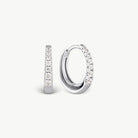 A pair of silver huggie hoop earrings with clear pavé-set stones, shown from side and front angles on a light gray background.