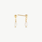A pair of gold post earrings with a small gold bead, a twisted wire detail, and a dangling baroque pearl on a light gray background.