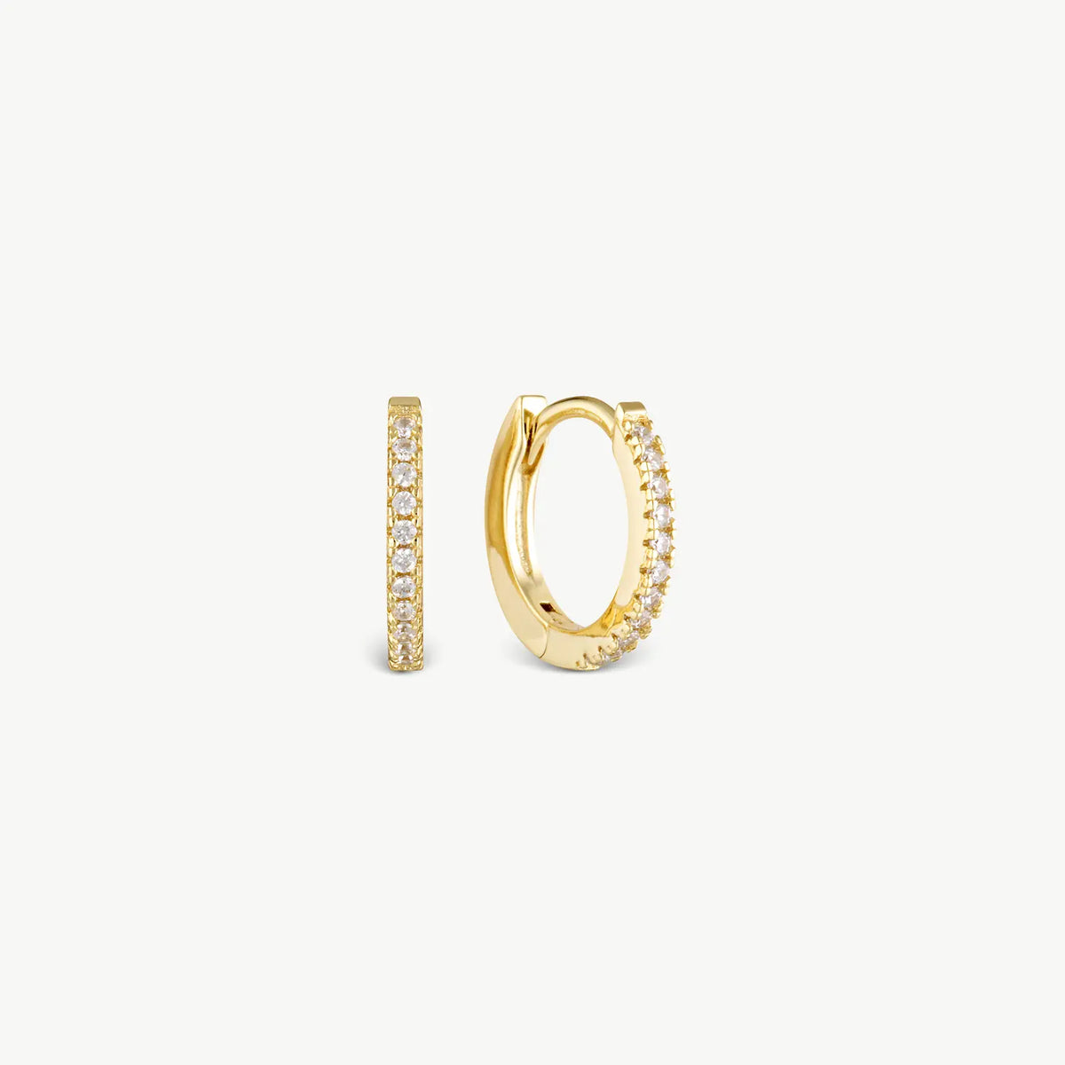 A pair of gold huggie hoop earrings adorned with small clear pavé stones, shown from both front and side angles on a clean off-white background.