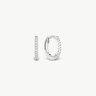 A pair of small silver huggie hoop earrings with clear pavé stones, shown from side and back views on a light gray background.