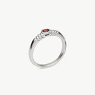 A silver ring with a textured, rope-like band and a small round red gemstone in the center, shown on a light gray background.