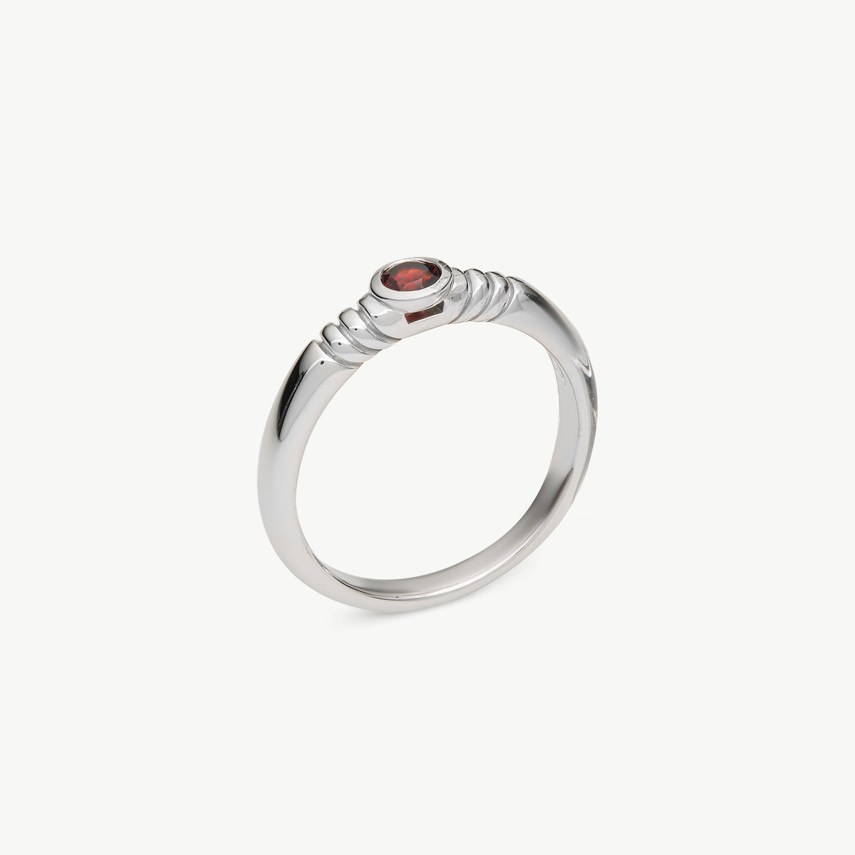 A silver ring with a textured, rope-like band and a small round red gemstone in the center, shown on a light gray background.