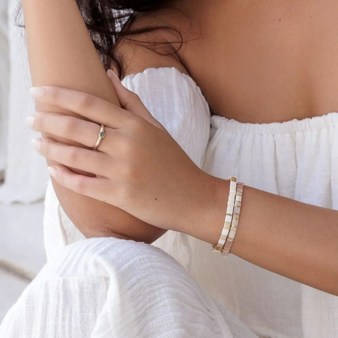Close-up of a person wearing a ring and bracelet, with a blurred background.
