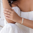 Close-up of a person wearing a ring and bracelet, with a blurred background.