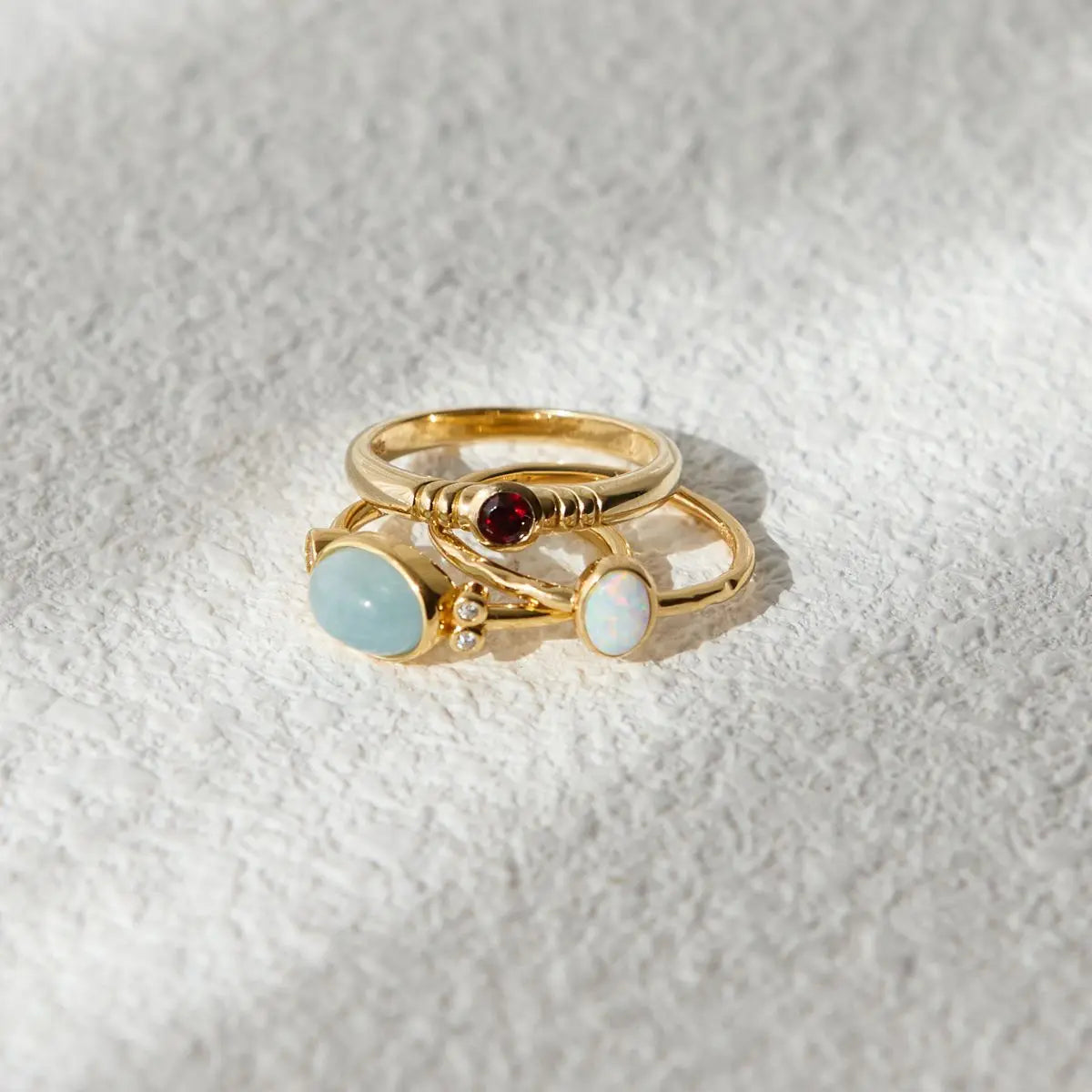 Gold ring with gemstones on a textured white background