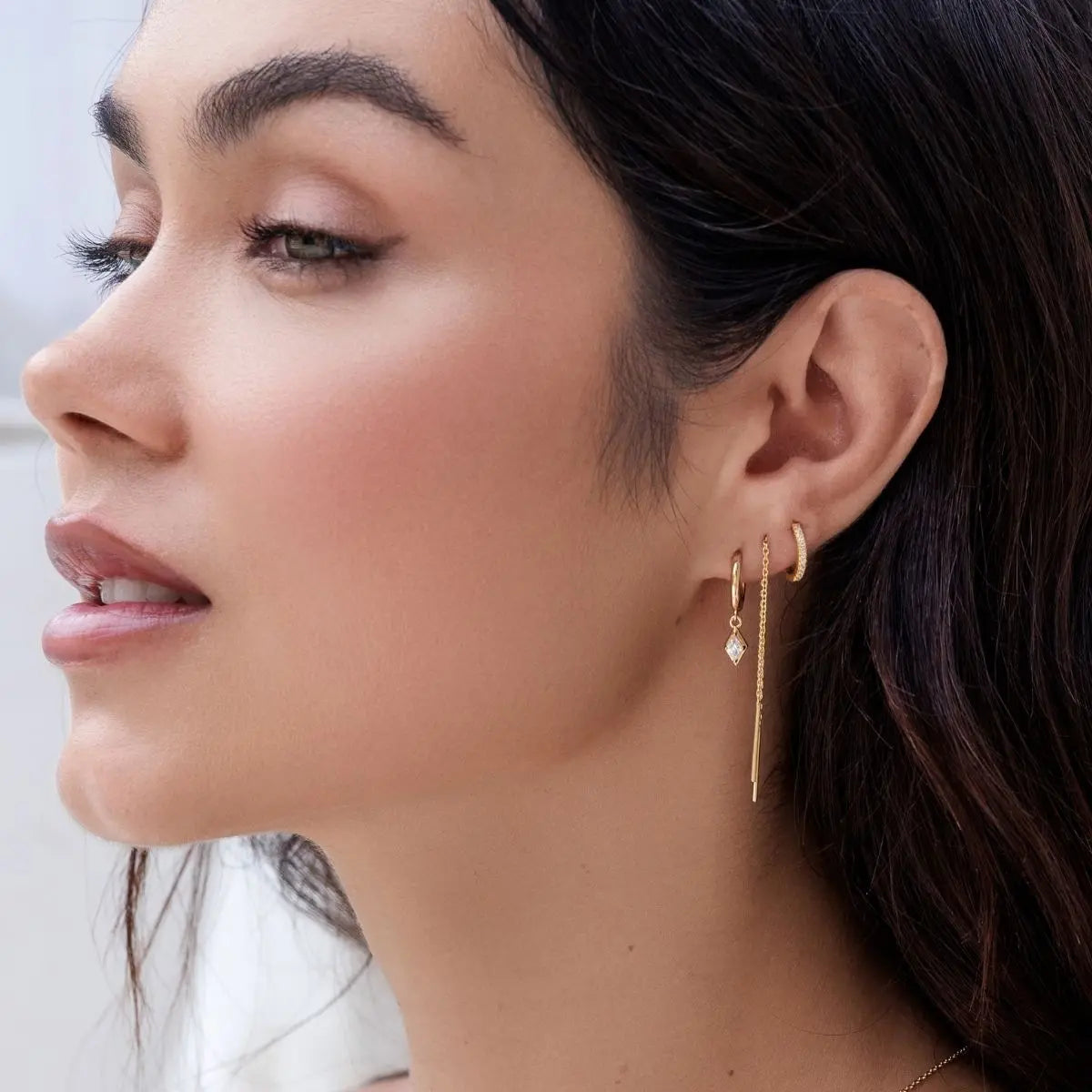 Close-up of a woman wearing gold earrings with a blurred background