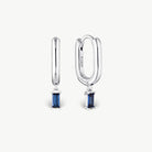 A pair of silver huggie hoop earrings with rectangular blue gemstone drops, shown on a clean off-white background. One earring is shown from the front and the other from the side, revealing an 'S925' engraving on the side hoop.