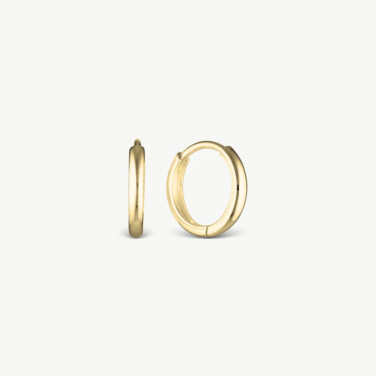 Gold thin huggie earrings on creabackground