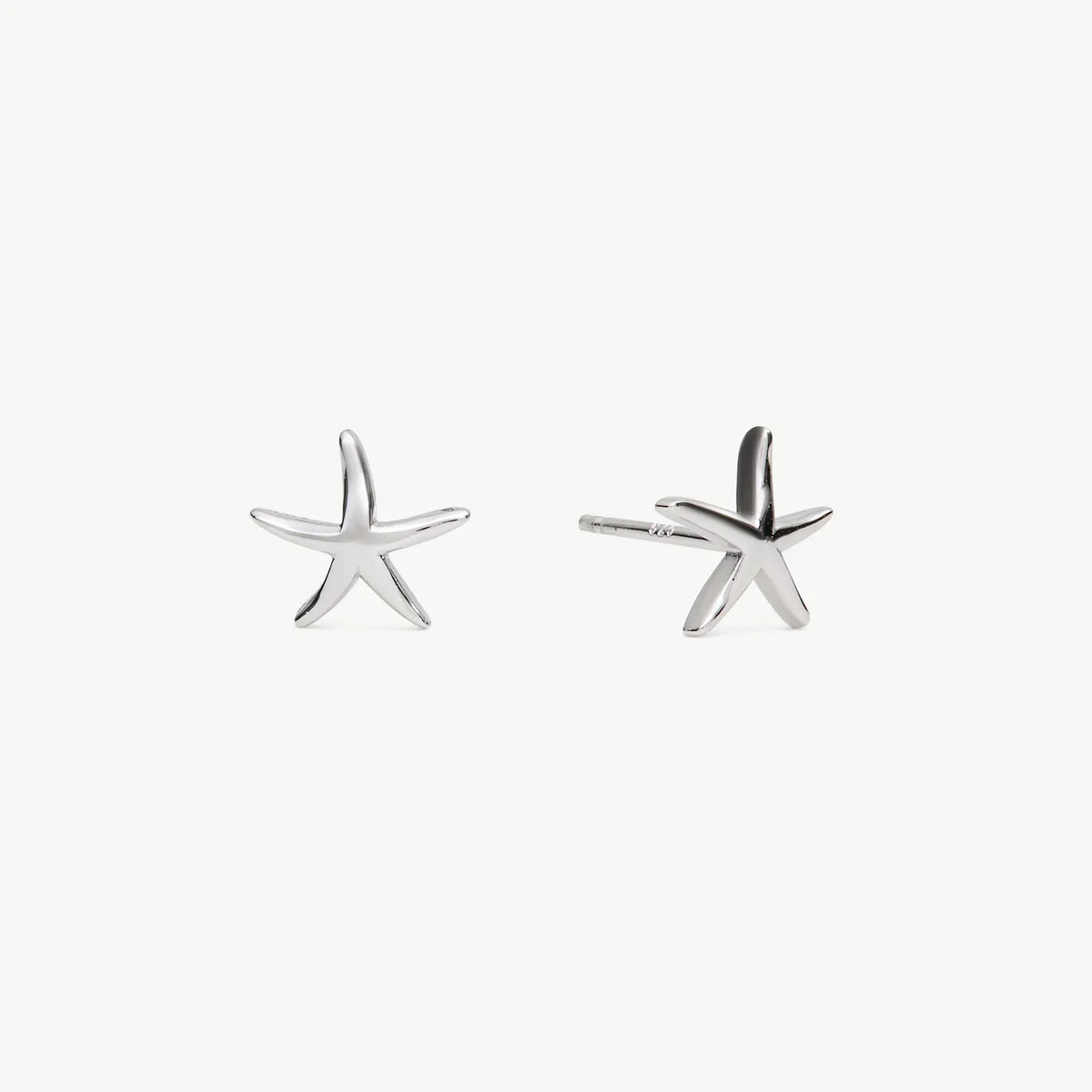 A pair of silver starfish stud earrings on a clean, light off-white background.