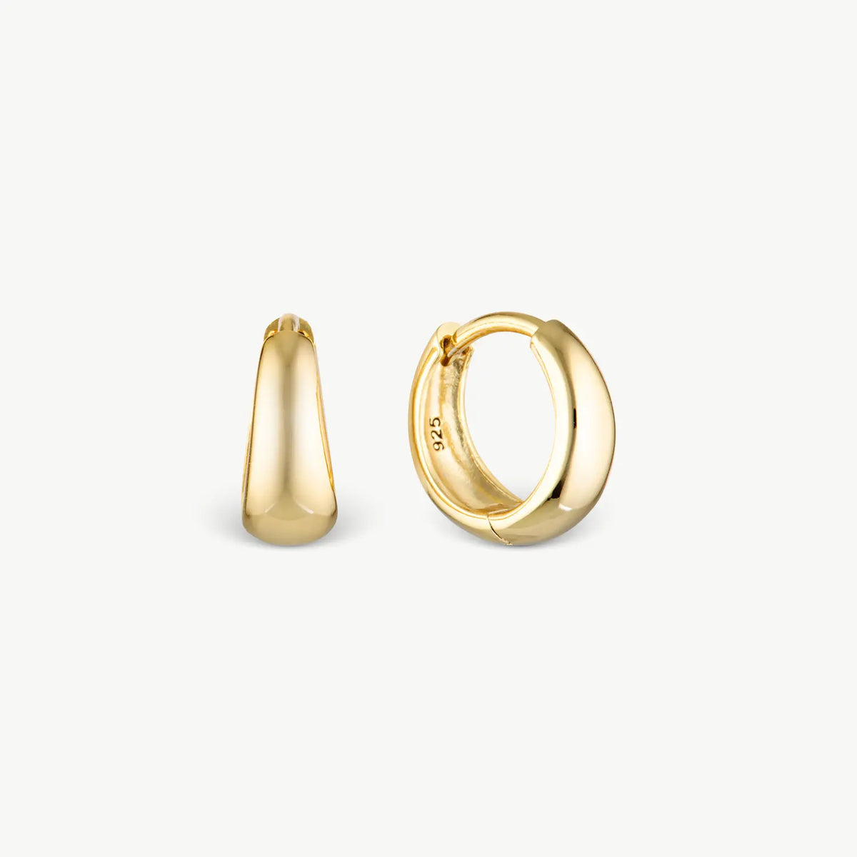 A pair of polished yellow gold huggie hoop earrings, one shown from a side profile and the other from a front-three-quarter angle, set against a clean off-white background.