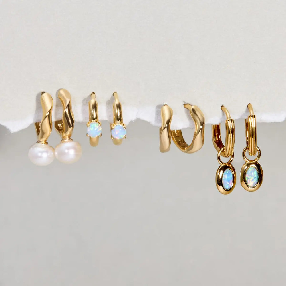 Set of gold hoop earrings with various designs on a white surface