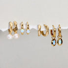 Set of gold hoop earrings with various designs on a white surface