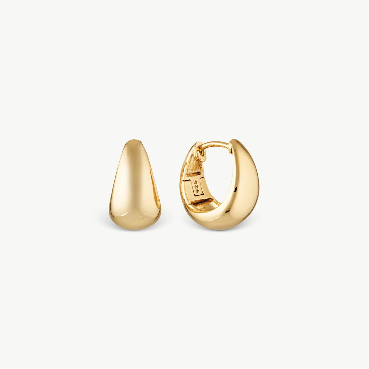 Wide gold tapering earrings on a cream background
